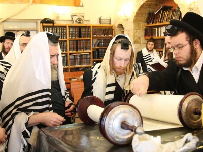 Jewish scholars gather around Torah scrolls during morning prayers 