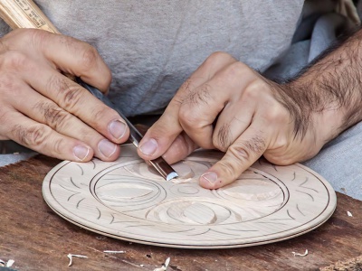A craftsman handcarving a decorative plate